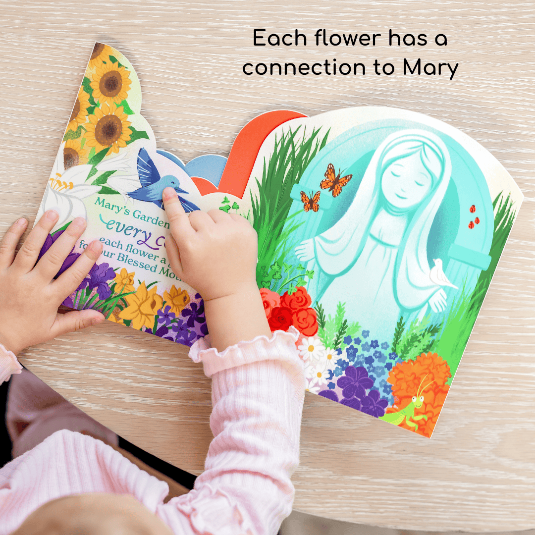 Child's hands holding a colorful book with illustrations of flowers and a figure, on a wooden surface.