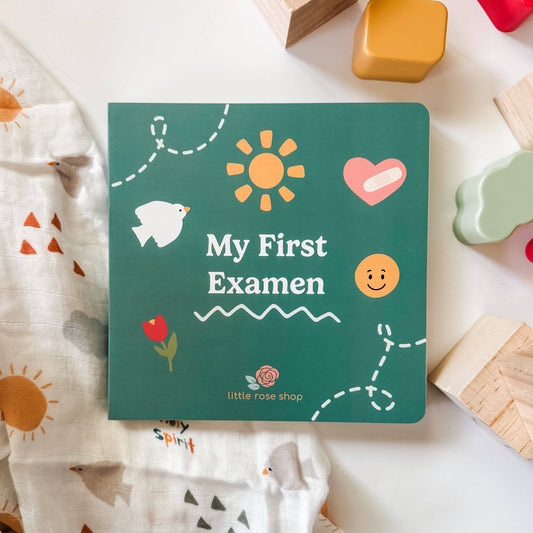 Children's book titled 'My First Examen' with colorful illustrations on a white surface with toys.