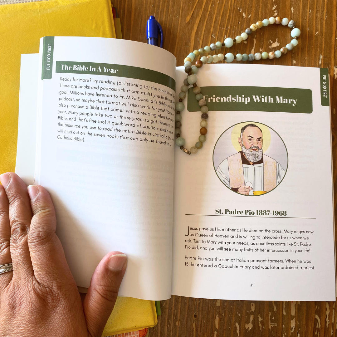 Open book with a page about St. Padre Pio, held by a hand on a wooden surface.