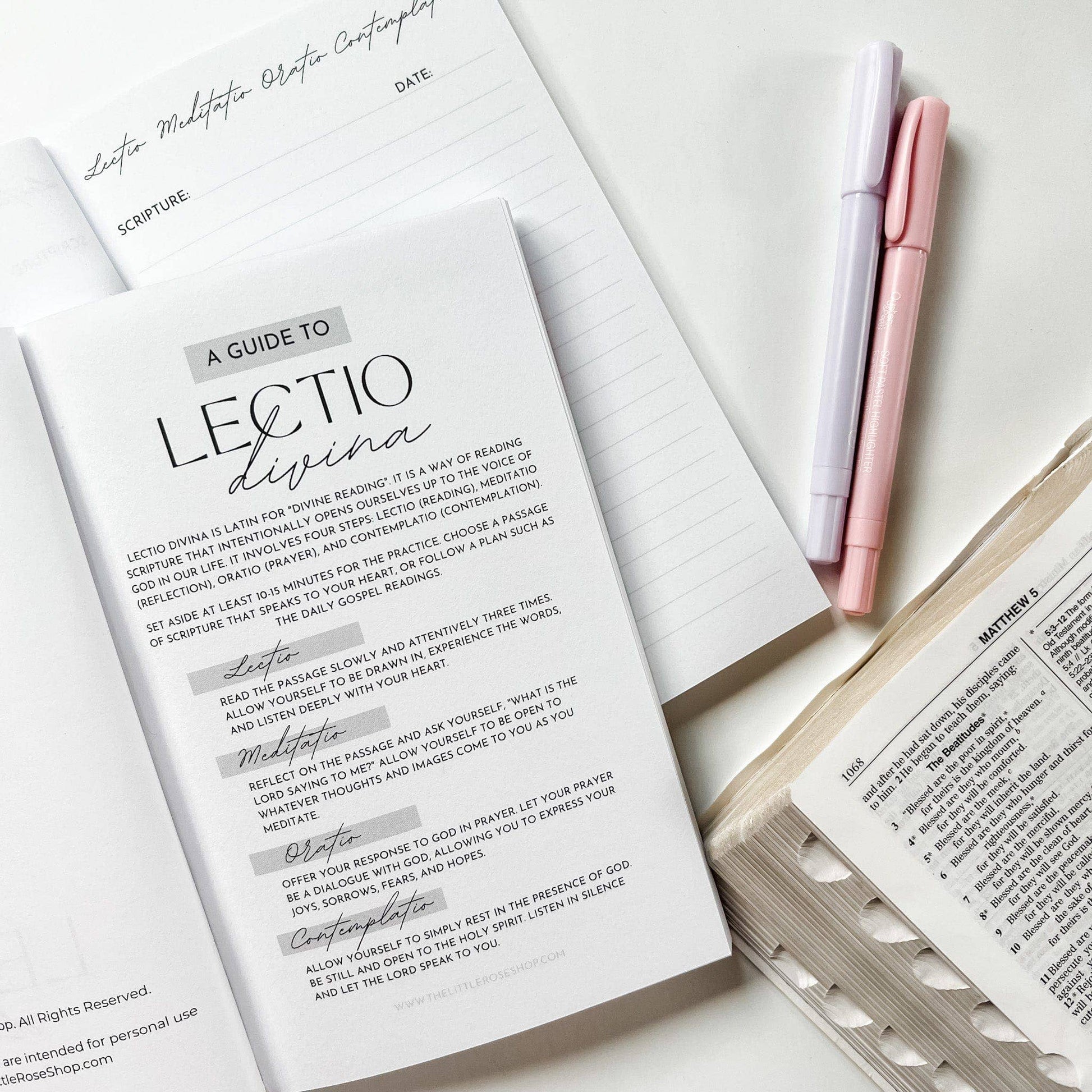 Open book with 'A Guide to Lectio Divina' text and two pens on a white surface