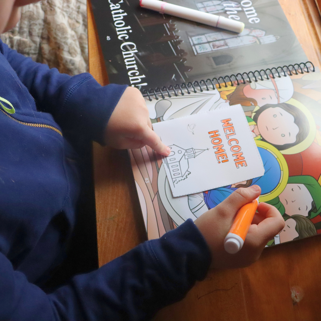 Child coloring a card with 'Welcome Home!' text on a table with educational materials.